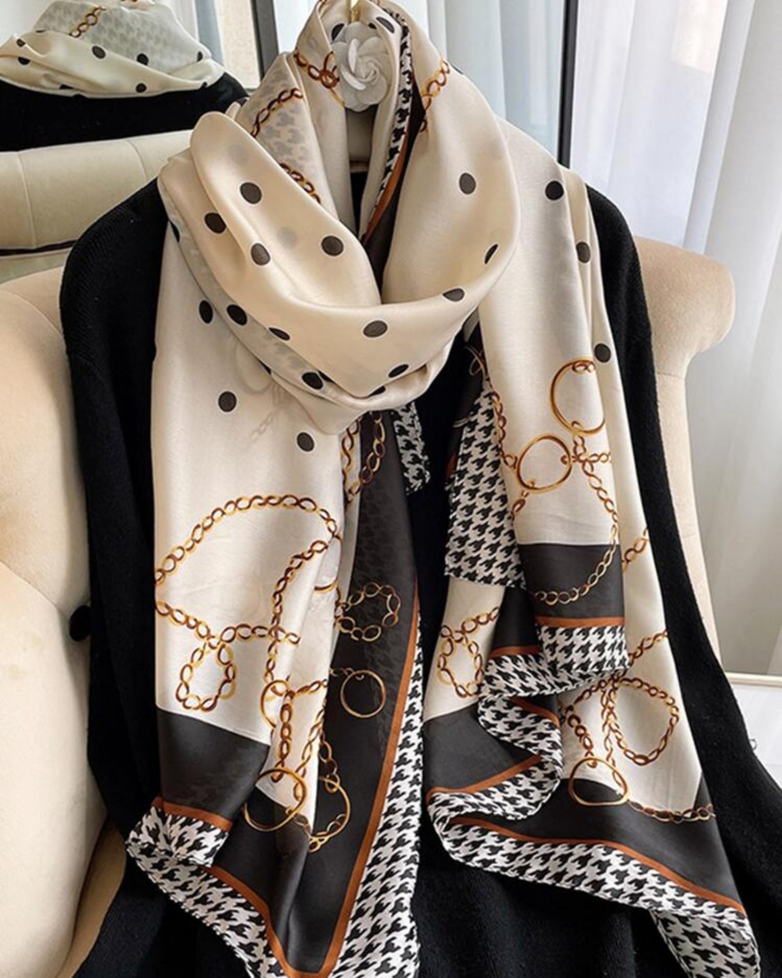 The Maison Trio Silk Scarf — draped on armchair showing polka dot, gold chain and houndstooth triple print
