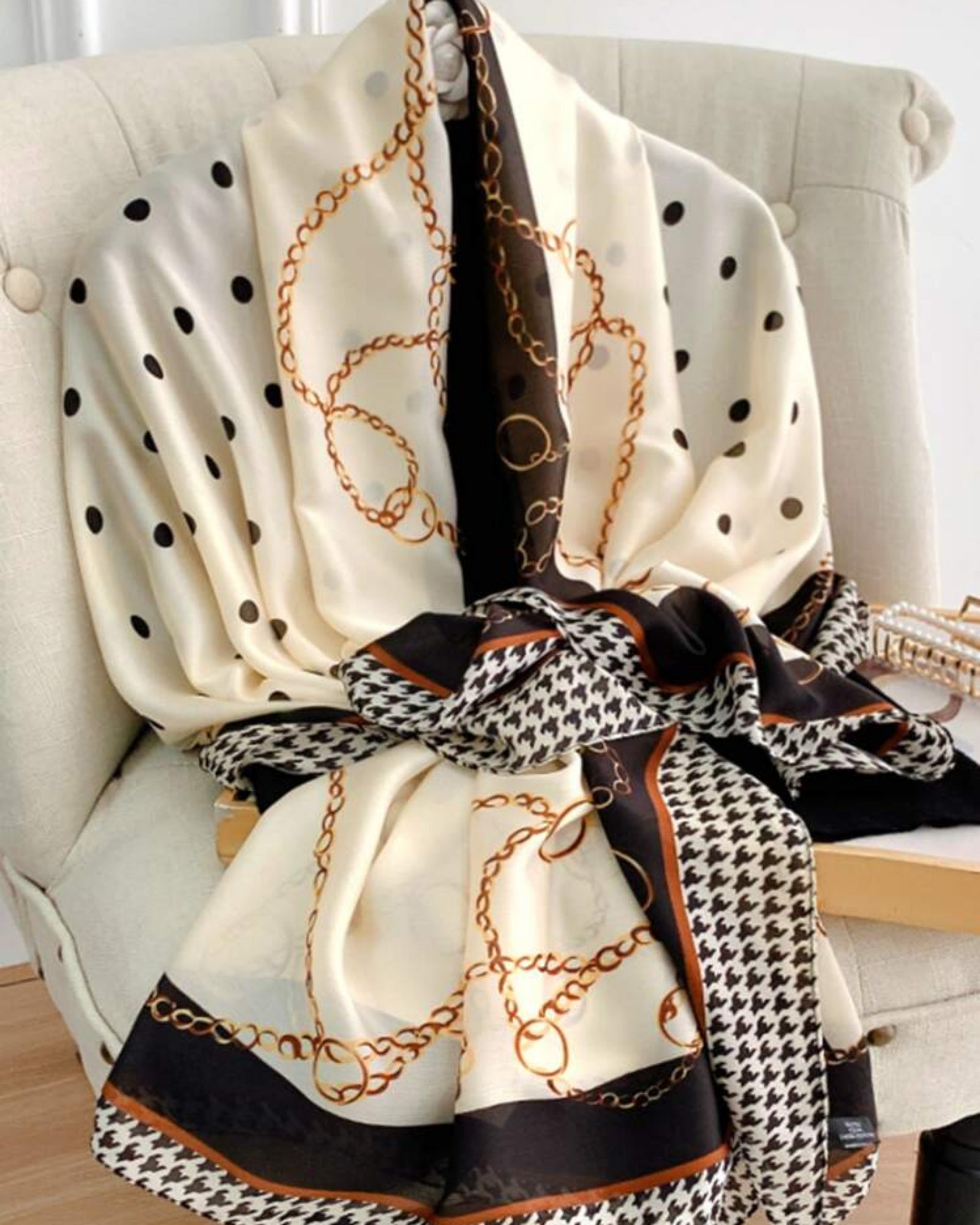 Maison Trio Scarf knotted on chair — full design view showing cream ivory base with black and cognac accents