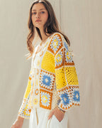Woman wearing a colorful crochet cardigan against a neutral background