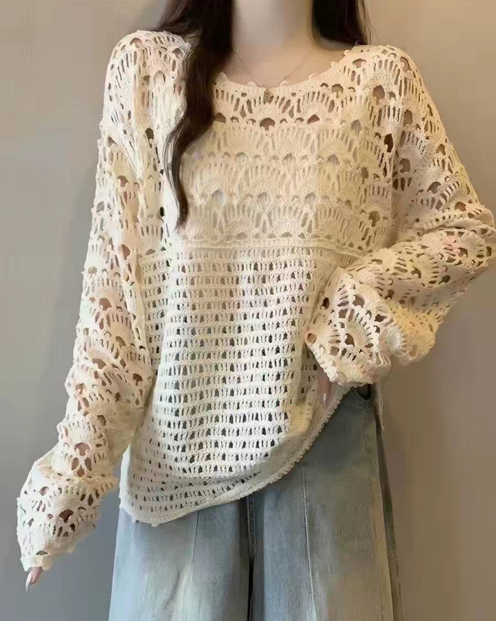 Beige crochet sweater worn by a person against a neutral background