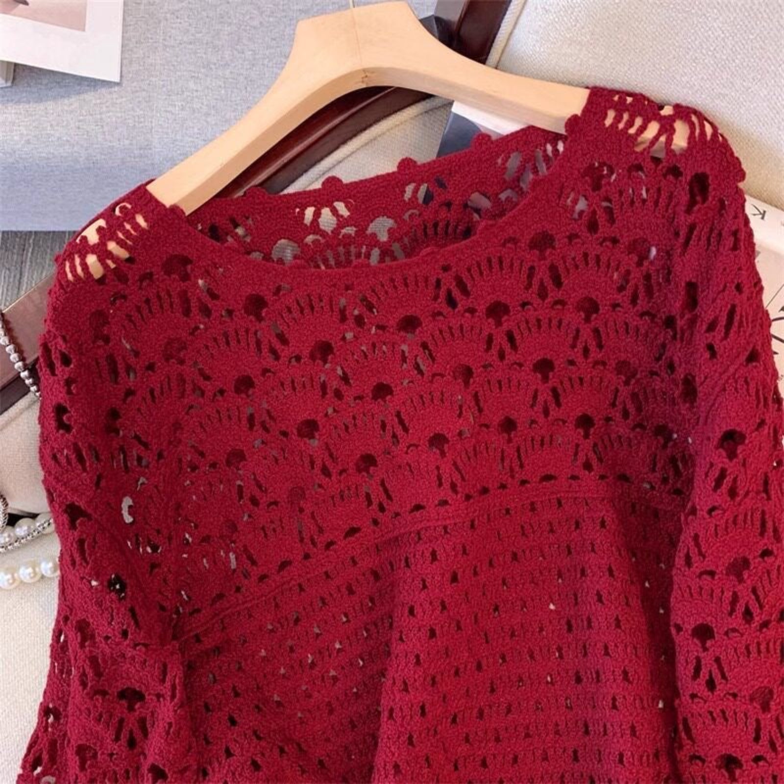 Red crochet top on a hanger against a neutral background