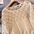 Beige crochet lace garment on a hanger against a neutral background