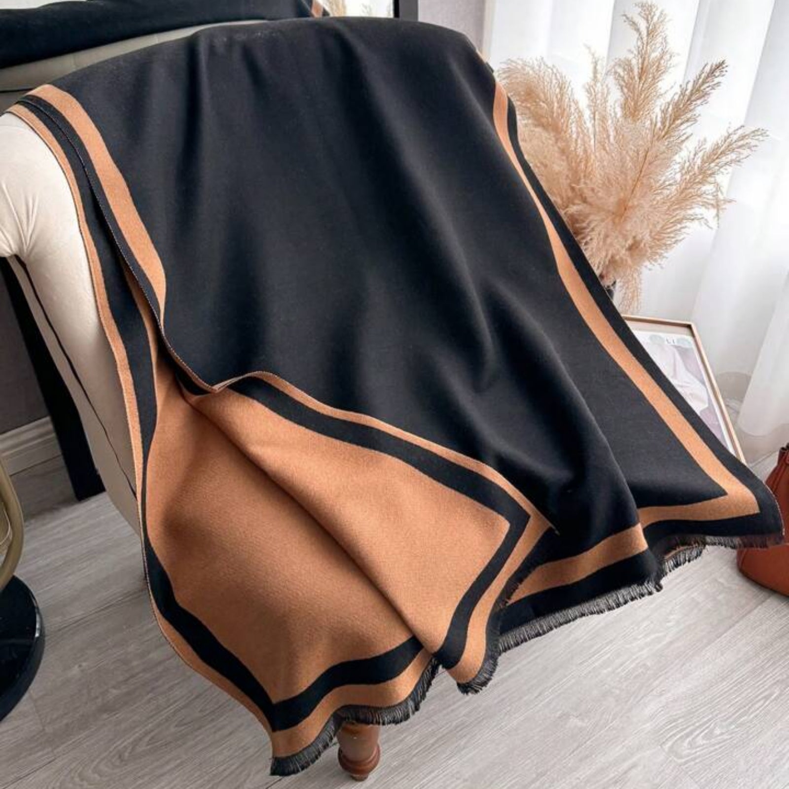 Black and brown blanket draped over a chair with a neutral background