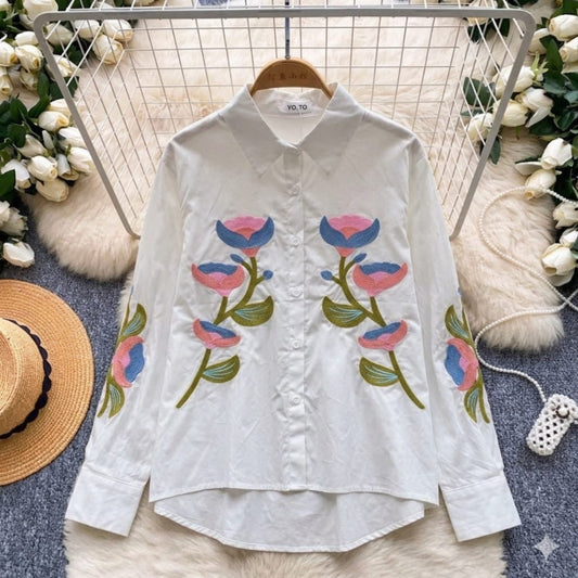 White shirt with floral embroidery on a hanger with decorative background
