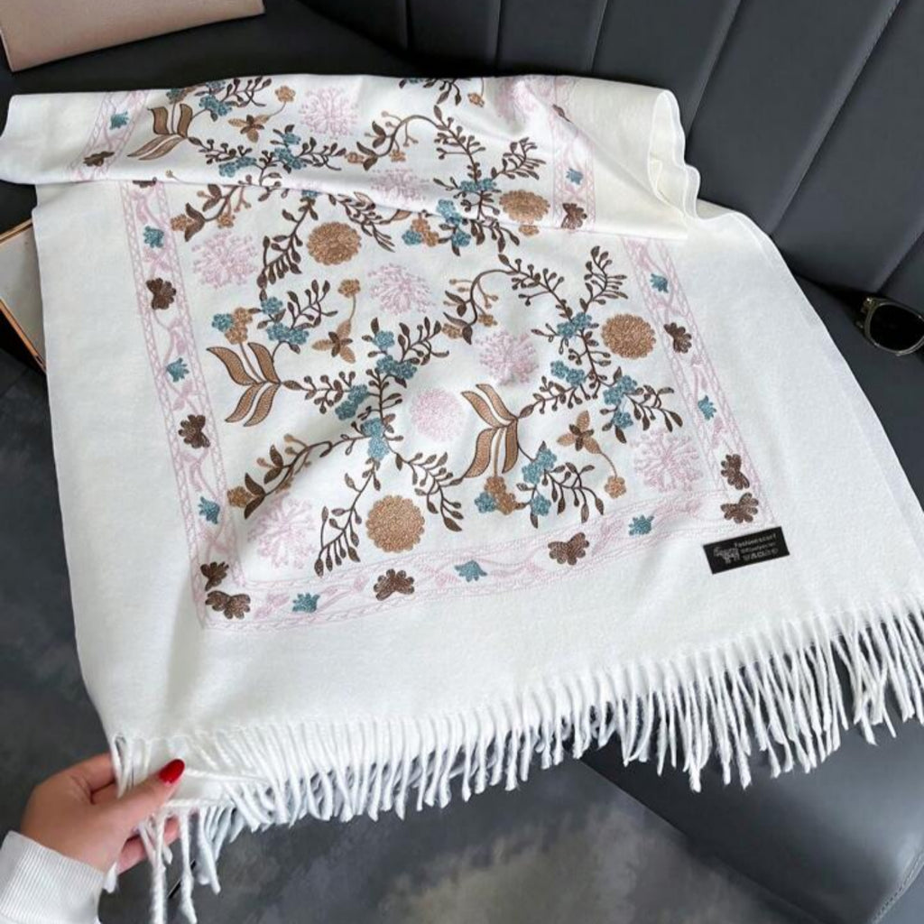 Floral patterned blanket with tassels held by a hand on a dark surface