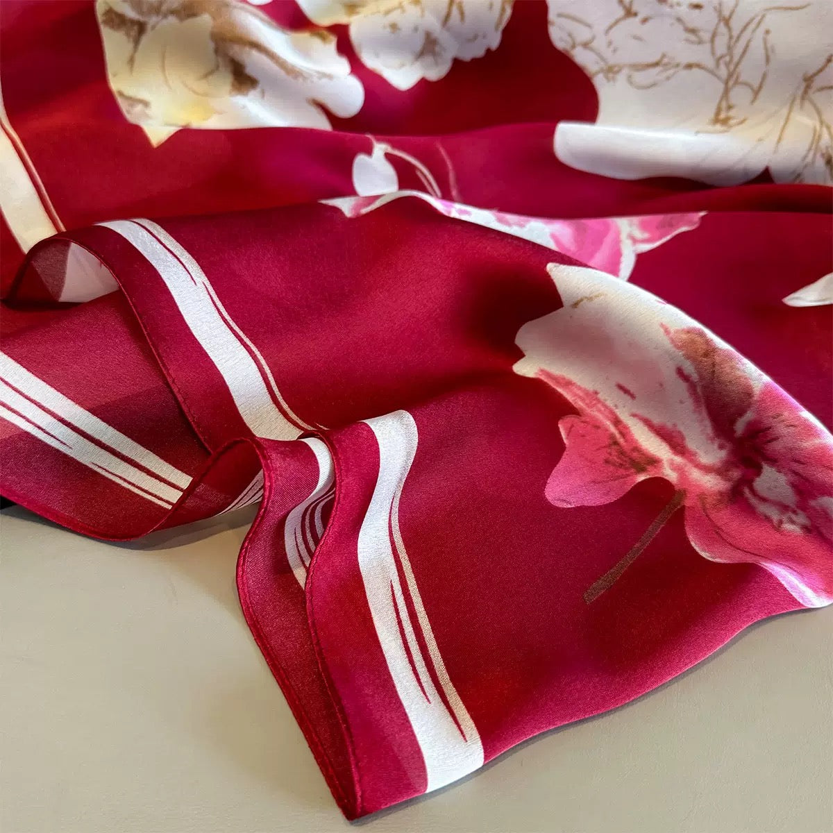 Red floral patterned fabric with white stripes on a beige surface