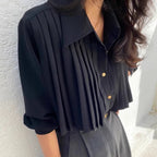 Back view of black pleated cape collar shirt showing elegant drape detail and pleated overlay