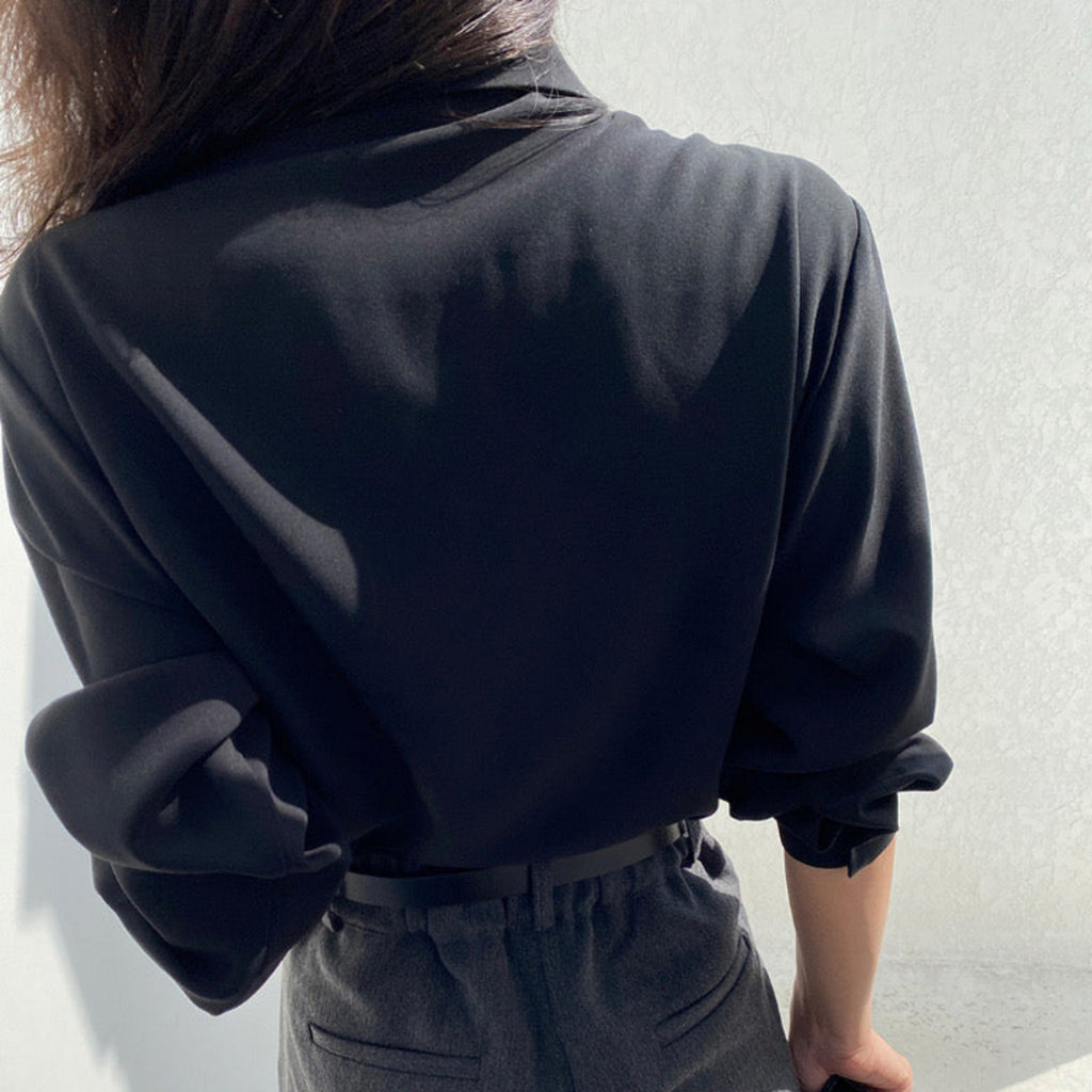 Back view of black pleated cape collar shirt showing elegant drape detail and pleated overlay