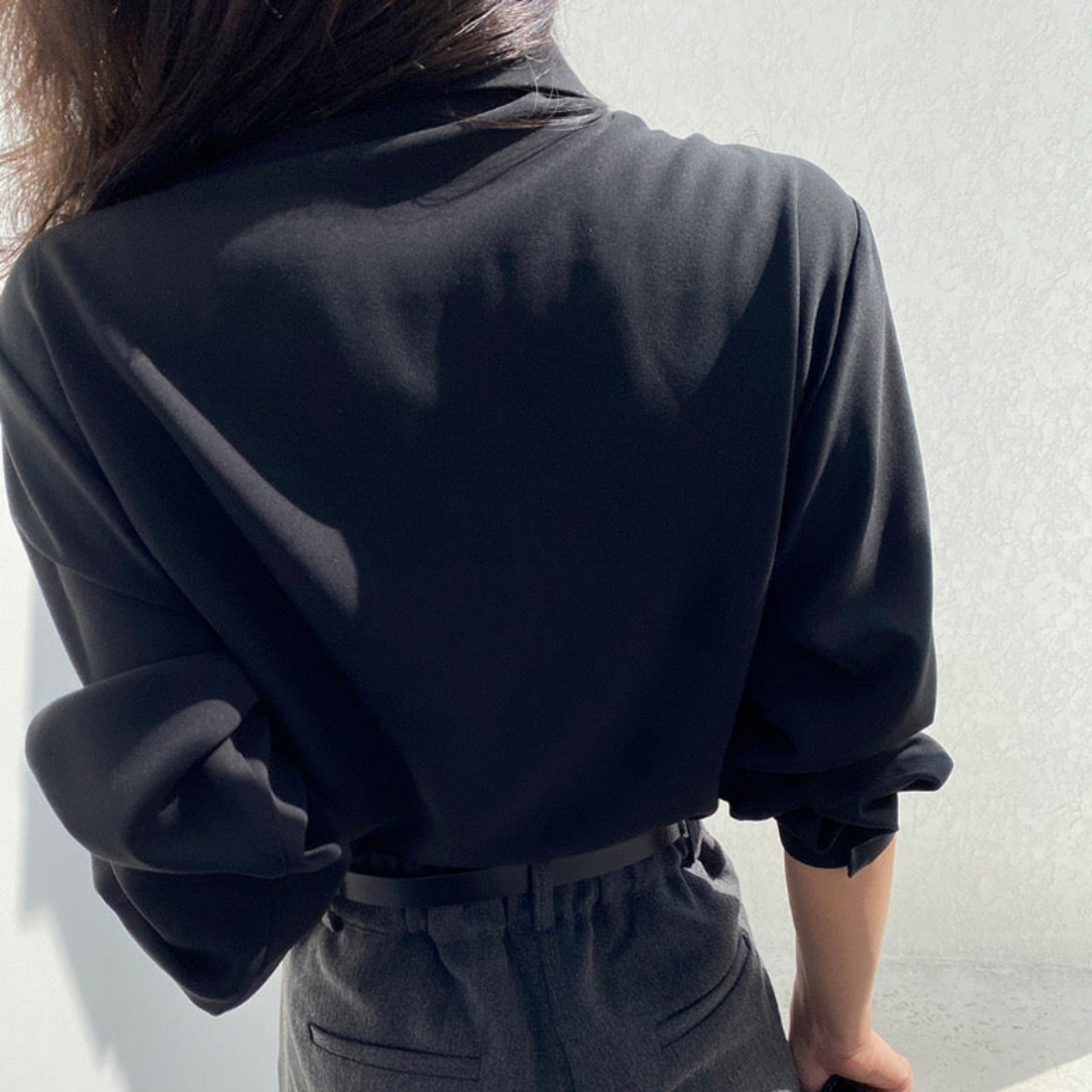 Back view of black pleated cape collar shirt showing elegant drape detail and pleated overlay