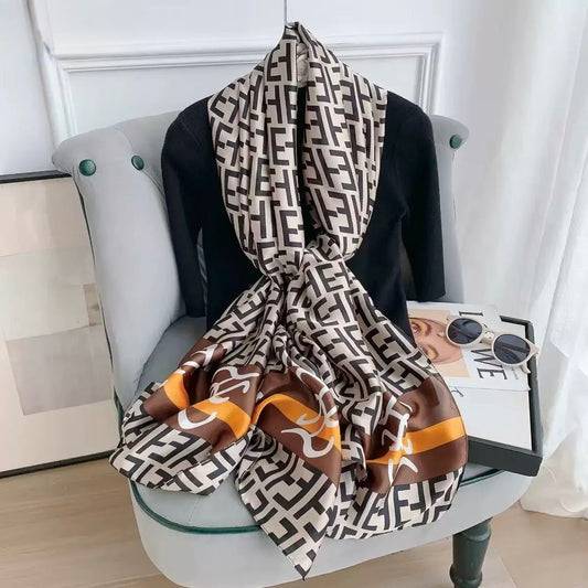 Black white brown orange designer logo scarf draped on chair - geometric monogram print silk stole
