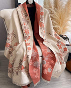 The Blush Botanica Reversible Wrap showing primary blush pink side with soft botanical floral motifs on faux cashmere fabric
