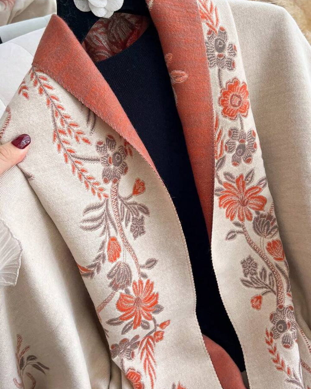 Close-up of The Blush Botanica Reversible Wrap showing soft faux cashmere fabric texture with delicate blush botanical floral motif detail
