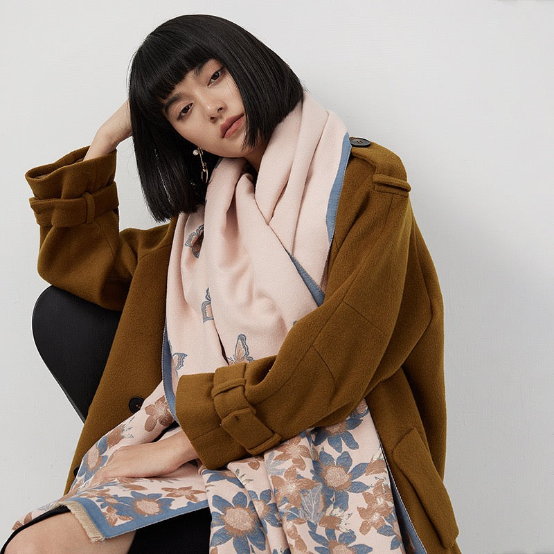 Close-up of Blush Butterfly & Floral Reversible Cashmere-Feel Wrap showing jacquard woven butterfly and floral motif texture on soft blush faux cashmere fabric
