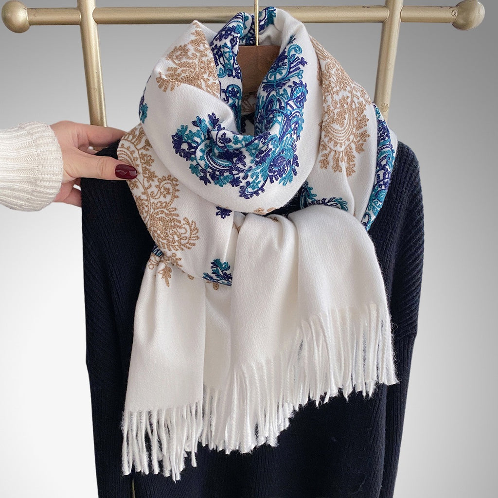 Bohemian Elegance Winter Scarf with Fringe looped around neck over black knitwear showing white ground with blue teal paisley embroidery and fringe detail

