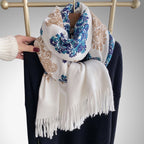 Bohemian Elegance Winter Scarf with Fringe looped around neck over black knitwear showing white ground with blue teal paisley embroidery and fringe detail
