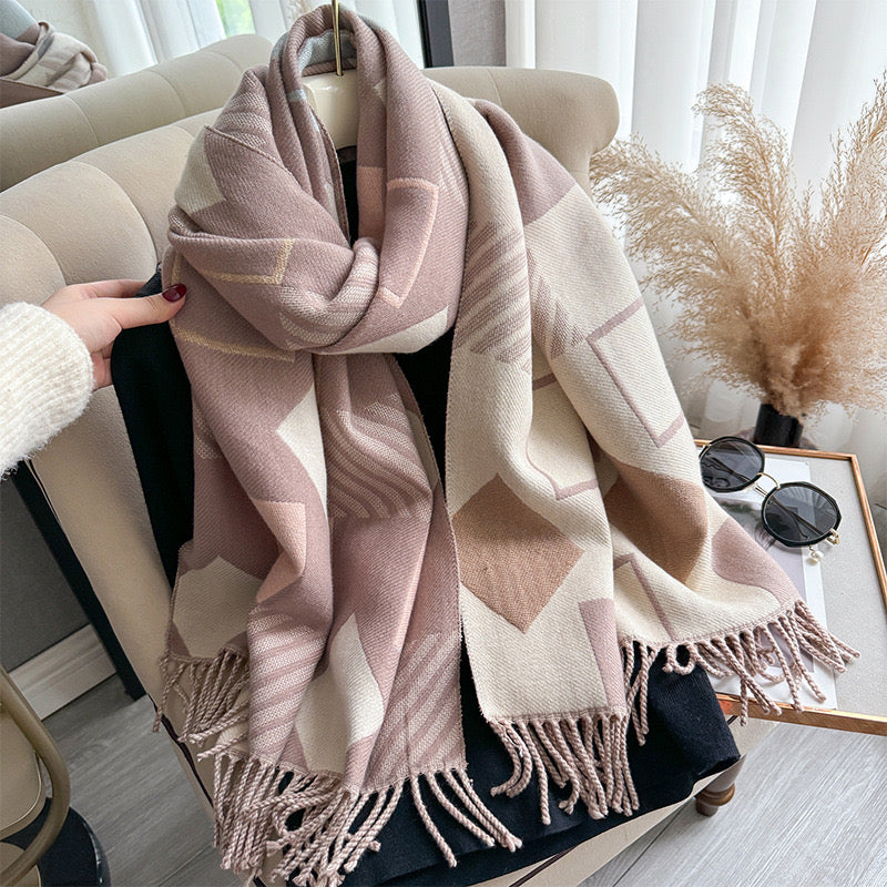 Chic Reversible Winter Poncho Shawl gathered in hand showing blush pink and beige geometric print with fringe tassel detail
