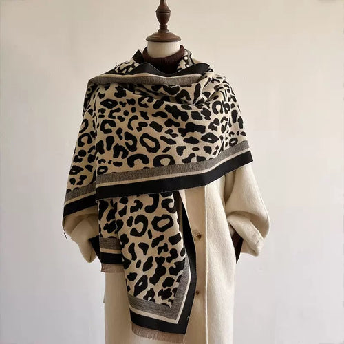 Classic Safari Leopard Knit Wrap in beige and black leopard print, elegantly draped over a cream coat.