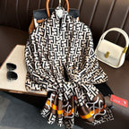Designer logo print imitation silk scarf in black white brown orange - geometric luxury scarf flat lay with accessories