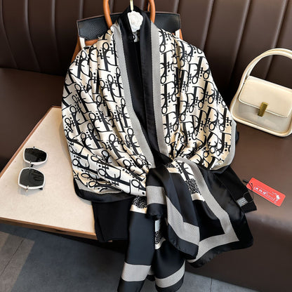Black and white patterned scarf on a hanger with sunglasses and a handbag in the background.