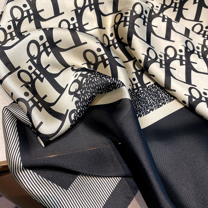 Close-up of designer logo print stole showing silk texture and striped border detail