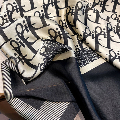 Close-up of designer logo print stole showing silk texture and striped border detail
