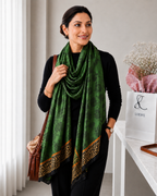 Woman wearing an emerald green imitation silk stole with an elegant floral jacquard pattern and bold leopard print border, styled over a black outfit.