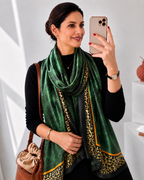 Emerald green imitation silk stole with leopard border draped stylishly on a woman, showcasing its glossy satin finish and luxurious drape.  