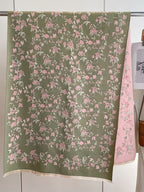Enchanted Rose Two-Tone Fringed Wrap laid flat showing full sage green floral jacquard rose print with cream fringe and dusty rose reverse visible
