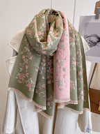 Enchanted Rose Two-Tone Fringed Wrap looped on hanger showing sage green side with pink rose floral print and cream fringe edge

