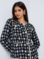 Black and white women’s knit cardigan featuring geometric patterns, pearl-effect buttons and elegant ivory braided edging.
