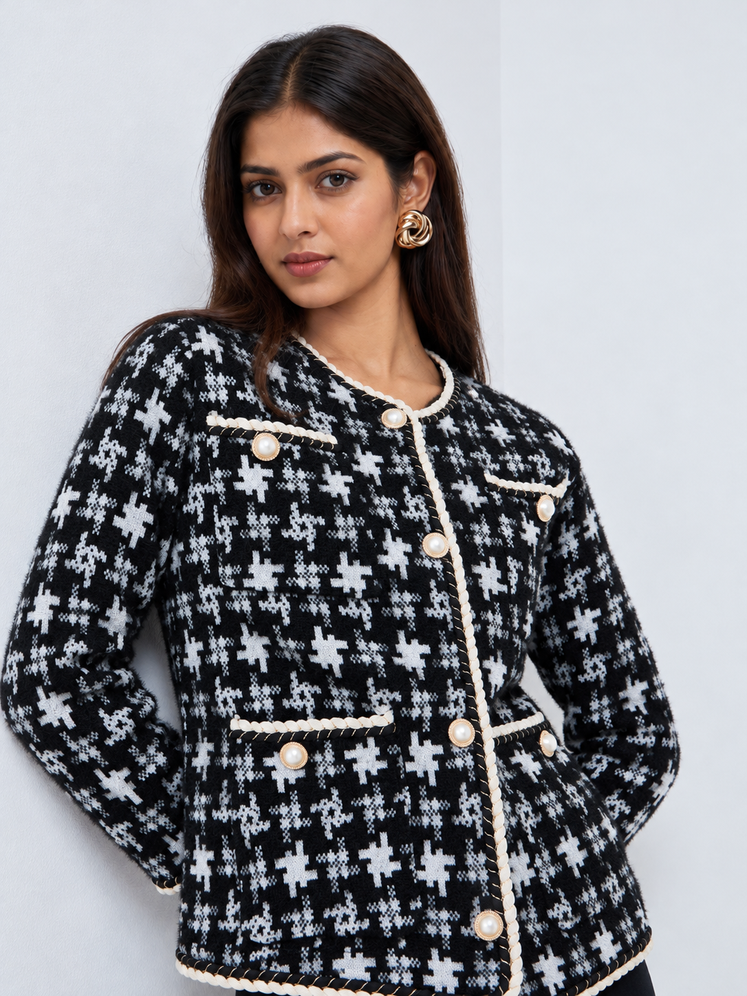 Black and white women’s knit cardigan featuring geometric patterns, pearl-effect buttons and elegant ivory braided edging.