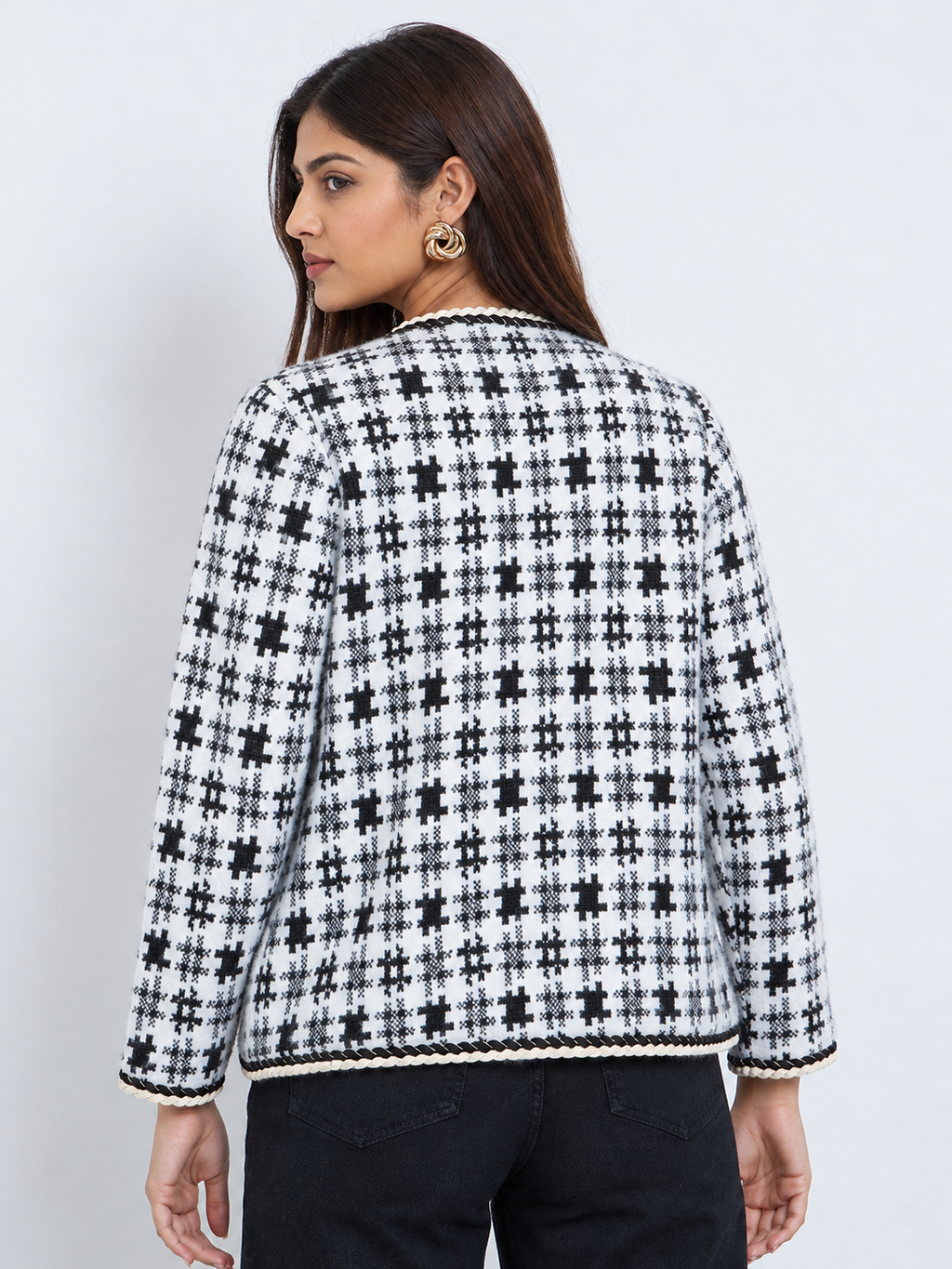 Back view of an ivory and black patterned women’s knit cardigan with full sleeves and braided edging.