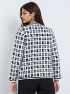 Back view of an ivory and black patterned women’s knit cardigan with full sleeves and braided edging.