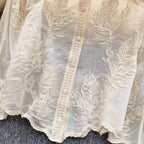 Close-up of floral embroidery with sequin and bead detailing on natural linen fabric