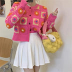 Woman wearing Garden Squares Crochet Cardigan in hot pink styled with white pleated skirt