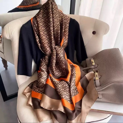 Flat lay of geometric print scarf showing Greek key border and orange brown striped detail