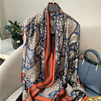 Gia Luxurious Paisley Print Silk Scarf in navy blue with intricate paisley motifs and rust satin border displayed in a flat lay.