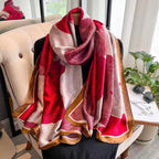 Hafi Elegant Floral Silk Scarf draped elegantly on a chair, showcasing the bold crimson floral pattern, soft ivory tones and golden border in premium imitation silk.  