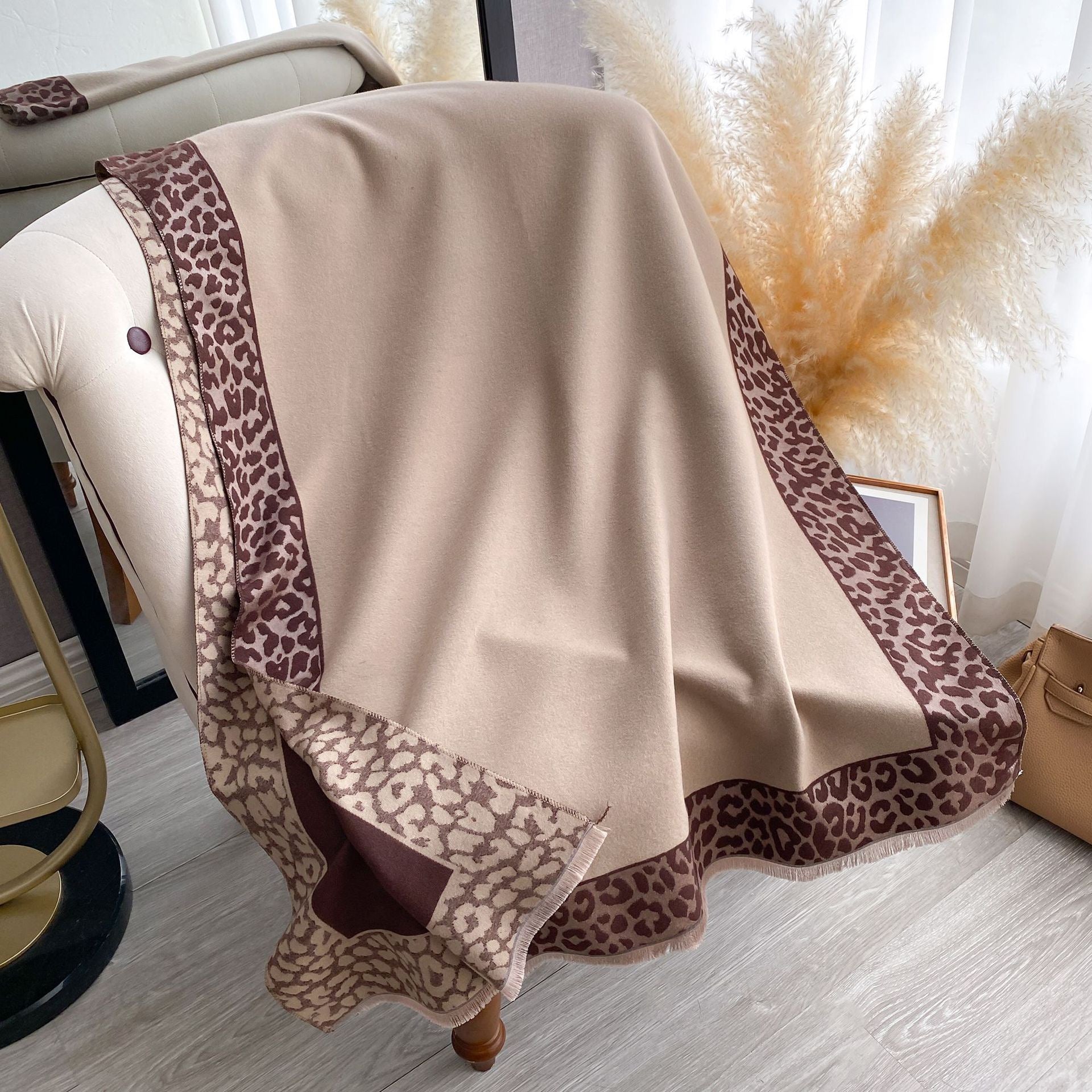 Hazelnut Leopard Trim Wrap draped over a chair showing reversible brown side with camel leopard border