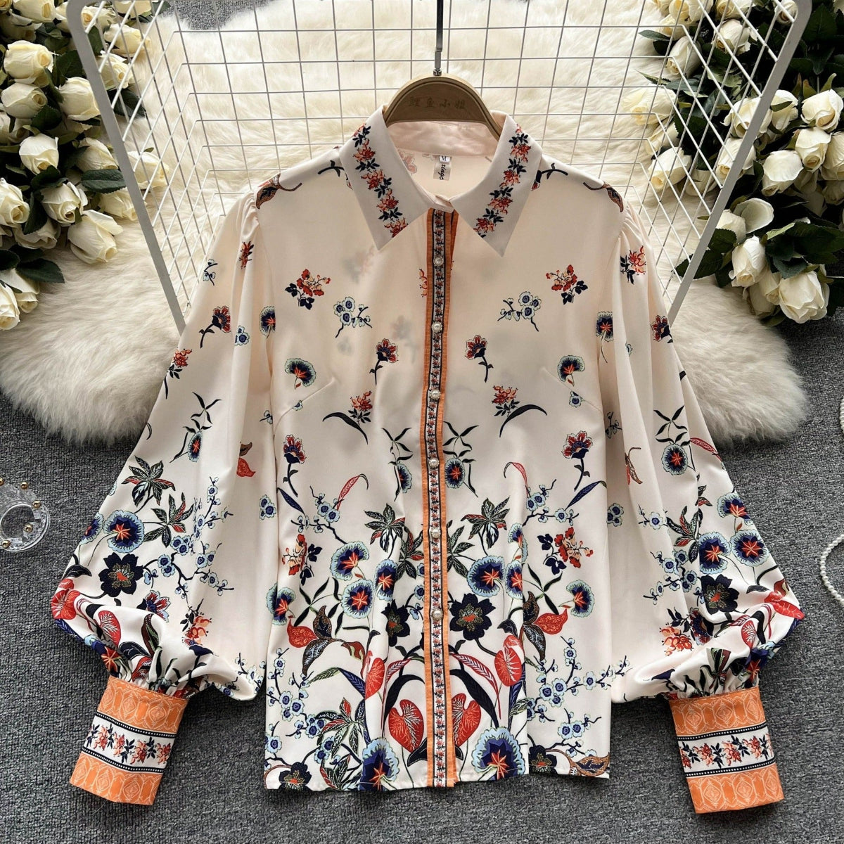 Jardin Bloom Satin Shirt displayed flat on hanger showing full botanical garden floral print with jewelled orange placket and contrast cuffs
