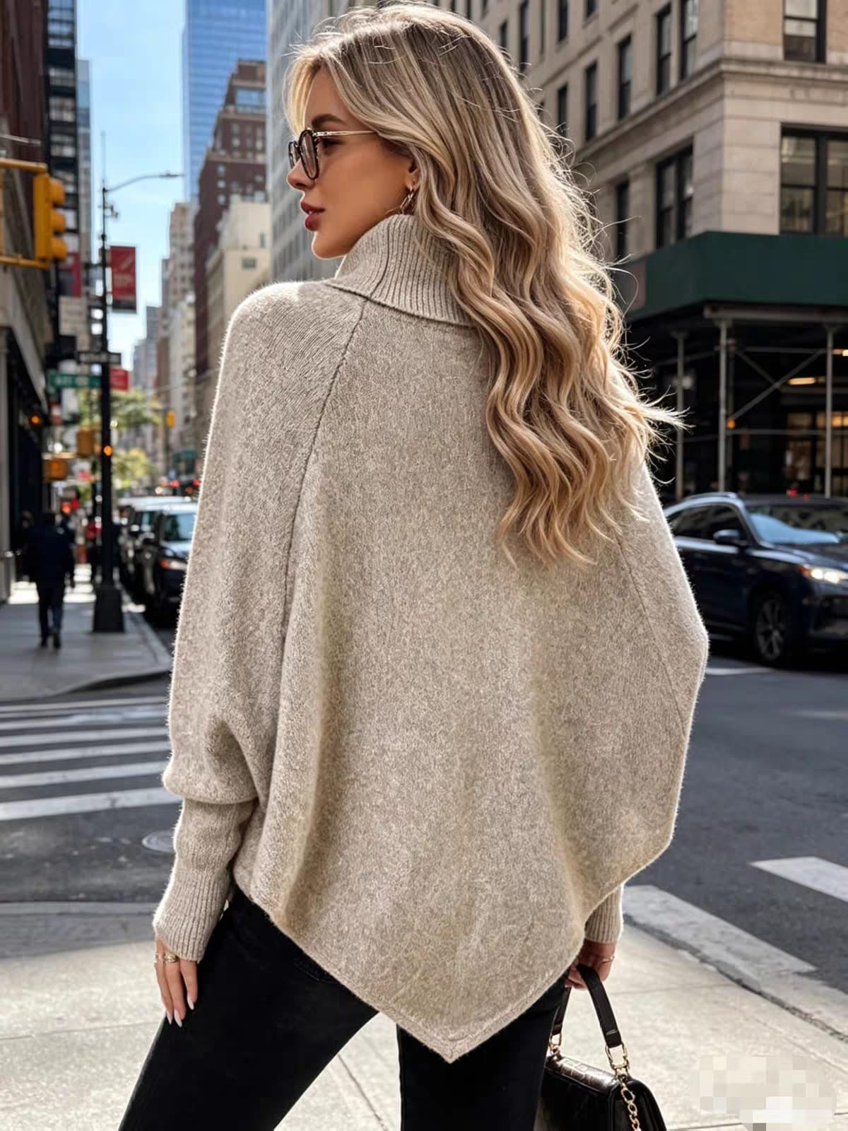 Back view of oatmeal taupe women's cable-knit cape sweater with relaxed draped silhouette