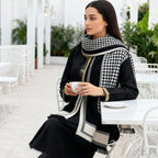 The Kensington Houndstooth Wrap draped over shoulders showing classic black and white houndstooth check on soft faux cashmere
