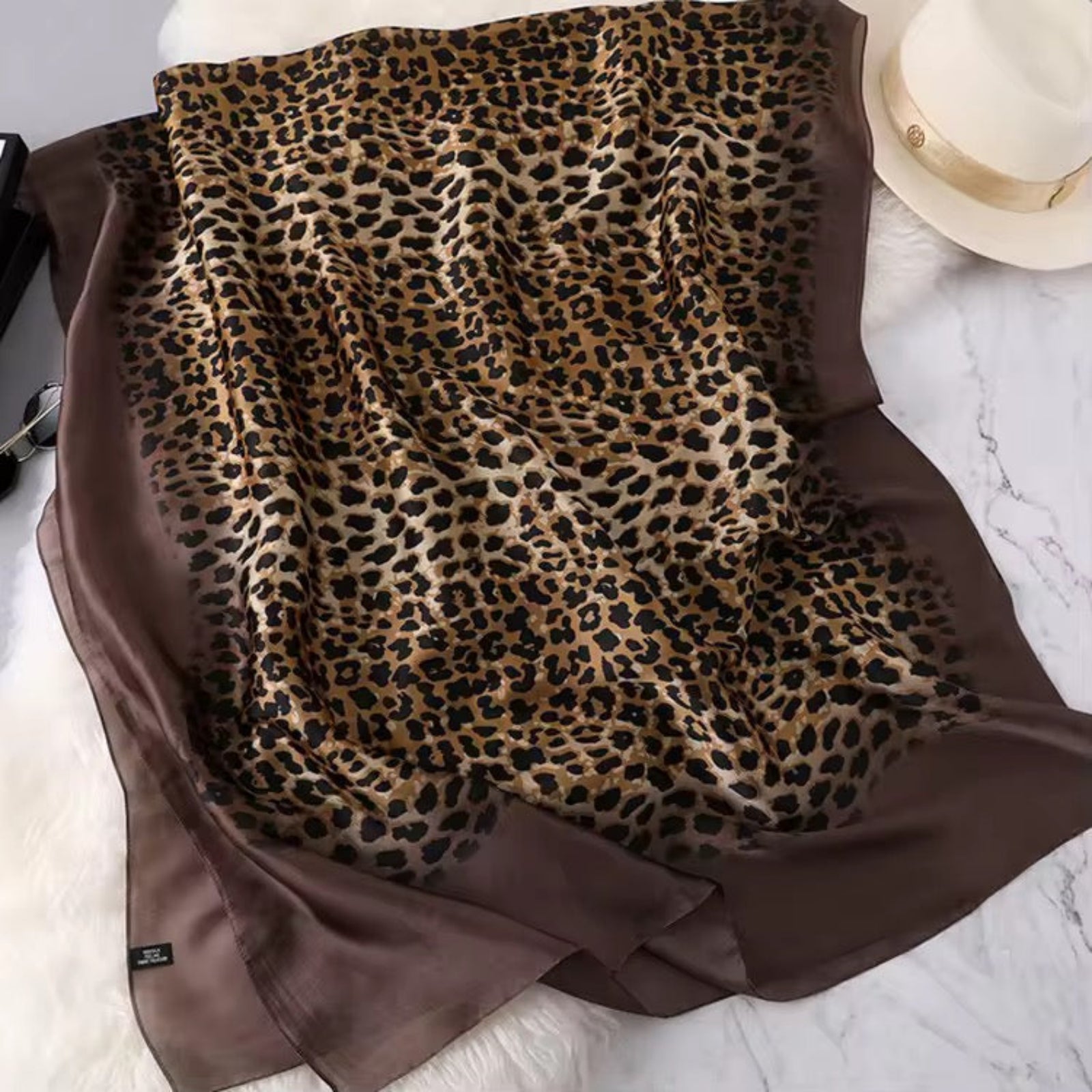 Full view of the Leopard Whisper Stole featuring an all-over leopard print with brown border.