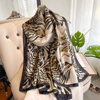 Luxe Savannah Silk Scarf draped over cream sofa showing leopard and zebra mixed animal print with black border
