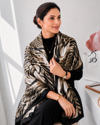 Woman wearing Luxe Savannah Silk Scarf draped over shoulders showing mixed animal print in black cream and gold tones
