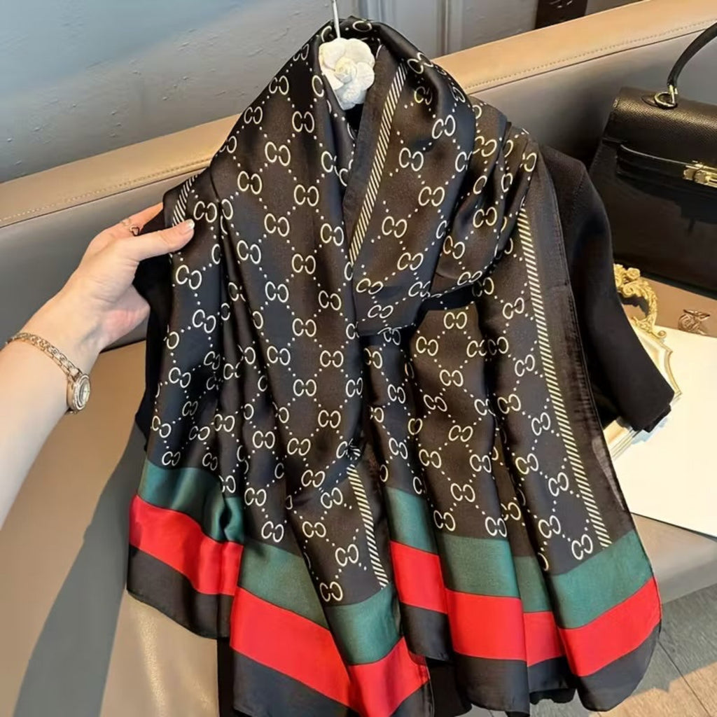 Folded Luxury Monogram Printed Silk Stole featuring an elegant black satin finish, intricate white monogram print, and bold emerald green and red striped borders. Premium silk stole designed for versatile styling and effortless sophistication.