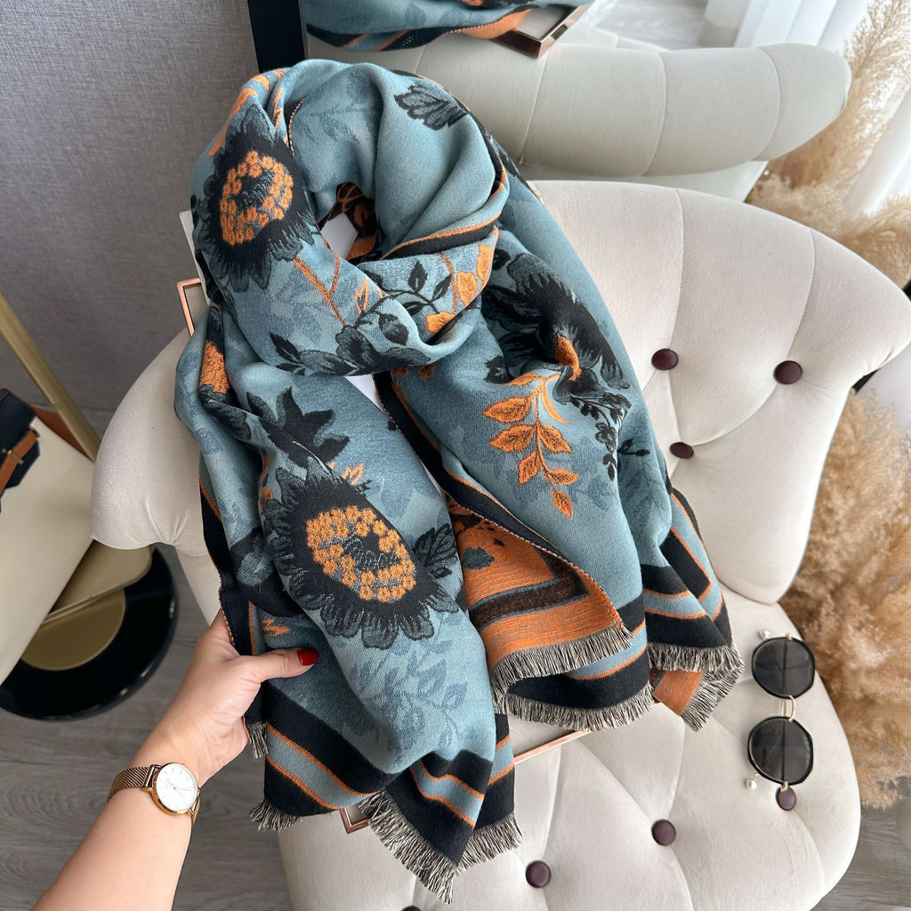 Luxury Reversible Oversized Floral Shawl Wrap held and gathered showing teal blue floral jacquard print with orange sunflower motifs and fringe edge

