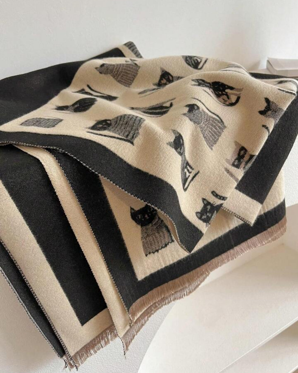 The Midnight Cats Reversible Wrap draped over shoulders as a wide shawl showing midnight base and illustrated cat print detail
