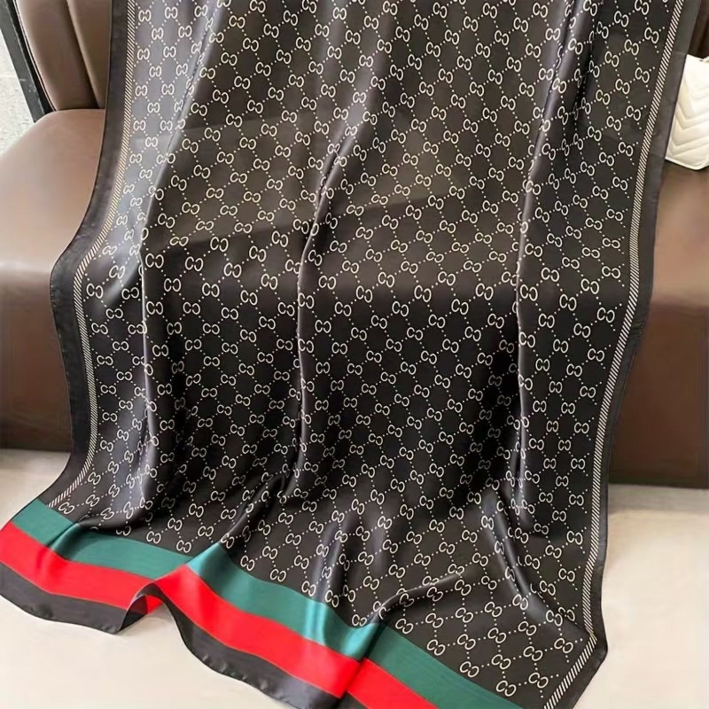 Black patterned scarf with red and green trim draped over a chair.