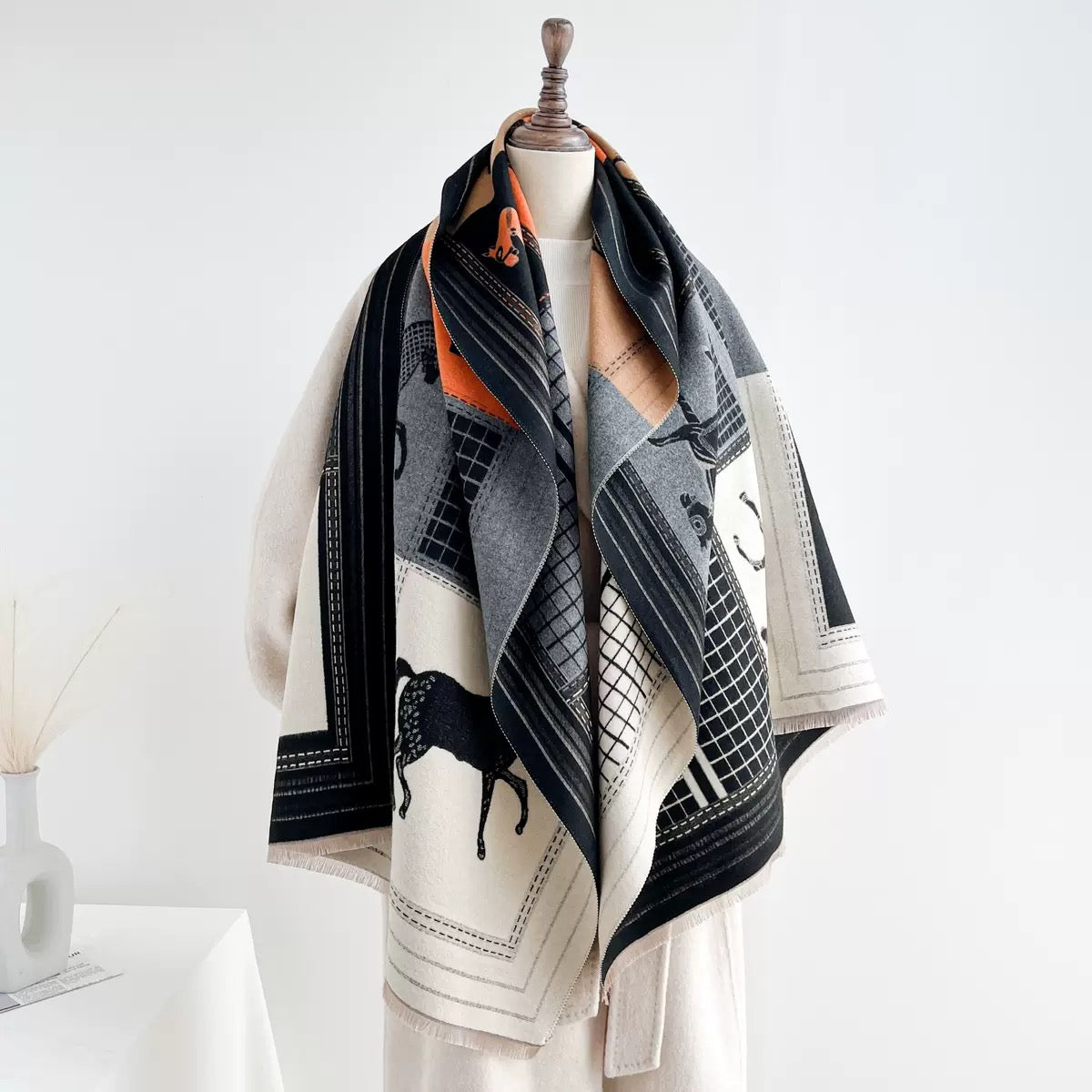The Noir Equestrian Cashmere Wrap worn as shoulder wrap showing full equestrian motif print on deep black faux cashmere

